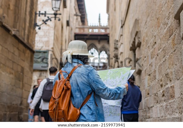 Latin tourist\
consulting the street map in the Gothic quarter of Barcelona\
(Spain), travel concept.