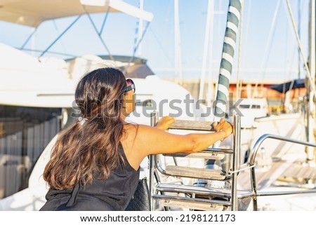 Latin woman boarding a sailboat in the Olympic port of Barcelona (Spain), travel concept.