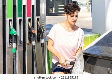 Latin Woman Filling Up Tank Of Her Car With Gasoline In Gas Station