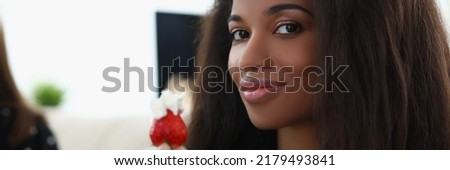 Latin woman hold fresh strawberry fruit with whipped cream on top