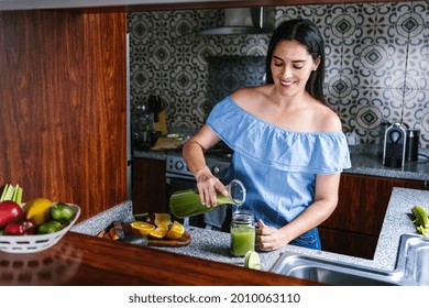 Latin Woman Making Green Smoothie Or Detox Juice In Kitchen At Home In Healthy Eating Concept In Mexico