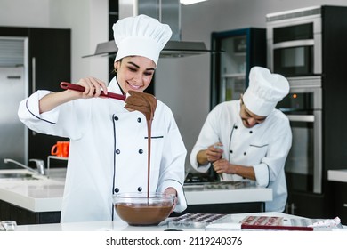latin woman pastry chef wearing uniform holding a bowl preparing delicious sweets chocolates at kitchen in Mexico Latin America