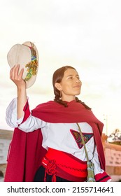 Latin Woman In Peasant Dress Holding Her Hat With A Colonial Bridge In The Background