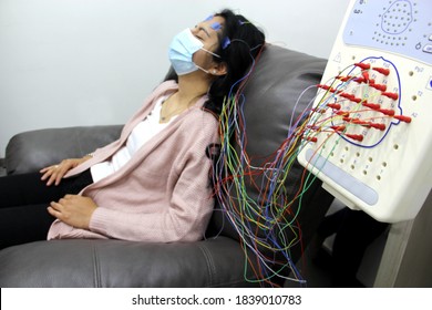 Latin woman with protection mask in medical tests, electroencephalogram and brain mapping in times of covid-19 contingency