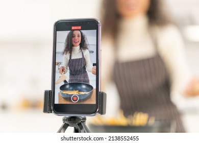 Latin woman shooting video and cooking at the kitchen for share on blog - Shutterstock ID 2138552455