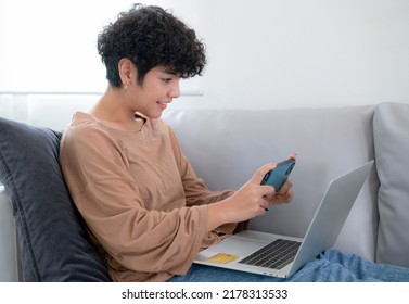 Latin Woman Shopping Online By Application In Computer Note Book And Pay Monry Online By Credit Card On Sofa