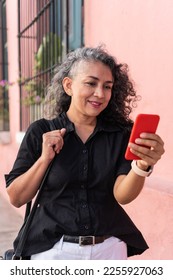 Latin Woman Using Mobile Phone In The Street - Shutterstock ID 2255927063