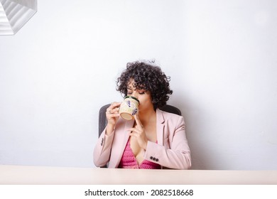 Latin Young Woman Drinking Cup Of Mexican Coffee In Office