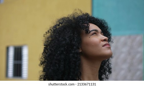 A latina black woman looking at sky with eyes closed feeling hopeful