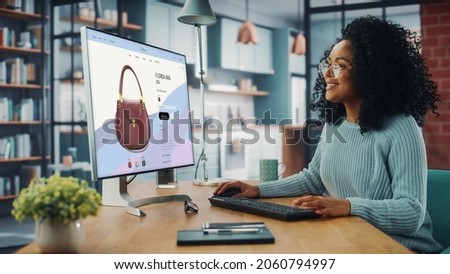 Latina Female Using Desktop Computer with Clothing Online Web Store to Choose and Buy Clothes from New Collection. Female Browsing the Internet at Home Living Room while Sitting at a Table