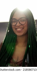 A Latina Girl With Box Braids Hairstyle Smiling At Camera Standing Outside With Flare