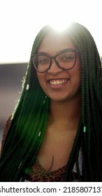 A Latina Girl With Box Braids Hairstyle Smiling At Camera Standing Outside With Flare