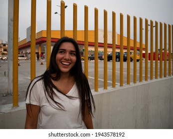 Latina Girl Outside A Supermarket Smiling With An Upward Gaze