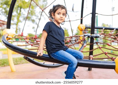 Latina girl playing on a climbing net, smiling at the camera in a Colombian playground - Powered by Shutterstock