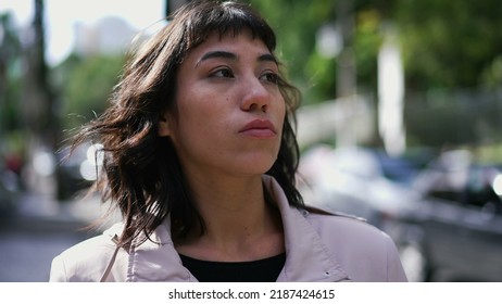 A Latina Hispanic Woman Walking In City Street With Serious Expression. South American Thoughtful Girl Walks In Sidewalk