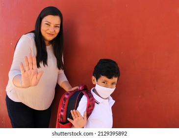 Latina Mom Prepares Her Son With A Face Mask To Protect Against Coronavirus And A Backpack For The Return To School In The New Normality Due To The Covid-19 Pandemic
