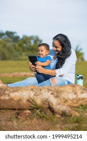 Latina Mom Taking Picture With Her Baby In The Green Field