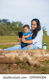 Latina Mom Taking Picture With Her Baby In The Green Field