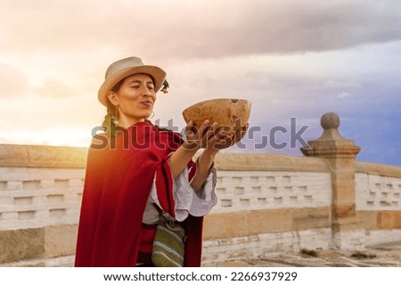 Latina peasant woman, wearing a hat and red shawl holding a gourd cup with a ceremonial drink