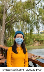 Latina Student Woman On Campus Wearing Surgical Mask Looking Straight At The Camera With Her Laptop Next To Her