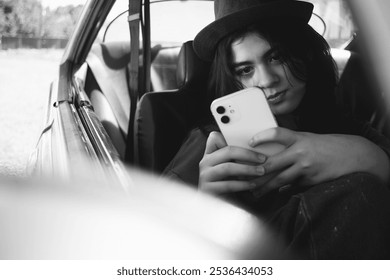 latina teenage girl sitting inside a car looking at her cell phone, black and white photo - Powered by Shutterstock