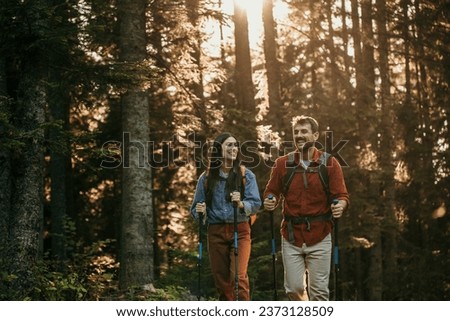 A Latina woman and her Caucasian companion embrace the great outdoors as they hike through the dense mountain forest, fully equipped with hiking gear