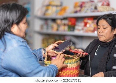 Latina Woman Paying Using A Mobile Phone In A Grocery Store