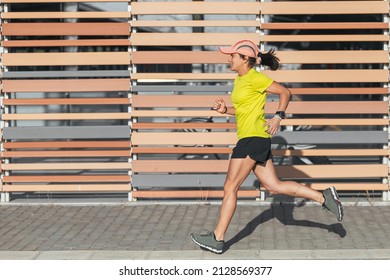 Latina Woman Running Outdoors In Profile With A Healthy Lifestyle. Yellow Color