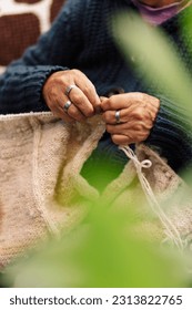 
					Latina woman, senior adult, happy and focused, in the living room using knitting needles and sheep's wool, concept of traditional everyday life, traditional weaver, selective focus.