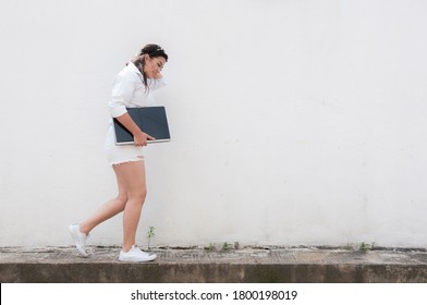 Latina Woman Walking Down The Sidewalk Loading Her Computer