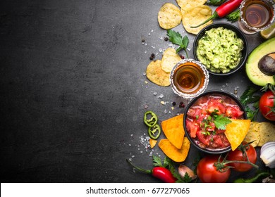 Latinamerican mexican food party sauce guacamole, salsa, chips and tequila on black table. Top view copy space. - Shutterstock ID 677279065