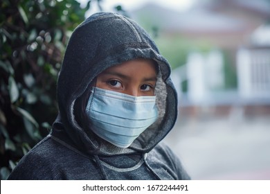 Latino 9 Year Old Girl Or Student Wearing A Hoodie Sweatshirt And Medical Face Mask To Prevent The Spread Of Infectious Diseases.