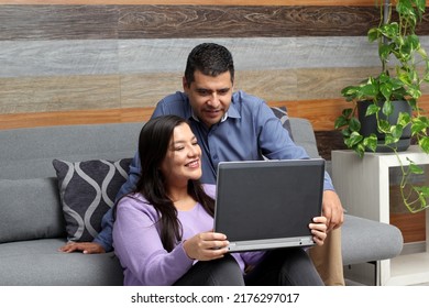 Latino adult man and woman couple use their laptop in the living room to shop online, make payments, plan trips, view photos and make video calls
 - Shutterstock ID 2176297017
