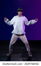 Latino Boy Dancing In Studio With Urban Outfit And Blue And Purple Background