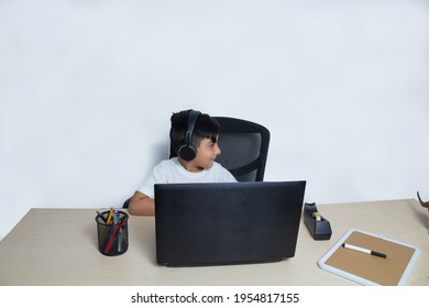 Latino Boy In Front Of Laptop Distracted In Online Class From Home By Quarantine