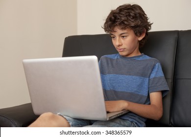 Latino Boy Sitting On Sofa With Laptop Computer.