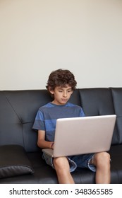 Latino Boy Sitting On Sofa With Laptop Computer.