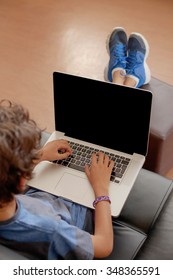 Latino Boy Sitting On Sofa With Laptop Computer.