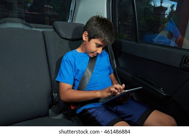 Latino Boy With Tablet On Back Seat Of The Car