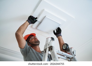 Latino Electrician Installing A Led Light On The Ceiling.