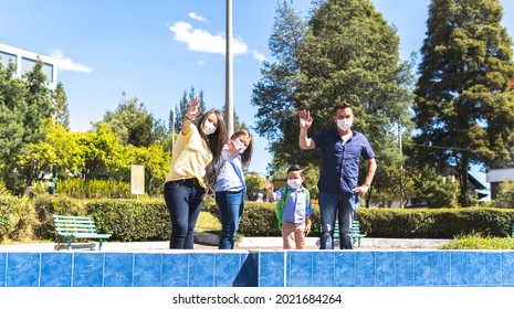 Latino Family With Mask Waving At Camera In A Park