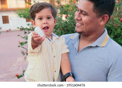 Latino Father Holding His Son While Eating Candy