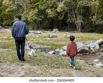 Latino father and son walking their toy poodle dog by a stream on an autumn afternoon. horizontal. Vacation in Argentina