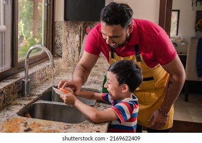 Latino father and son wash the dishes at home. - Shutterstock ID 2169622409