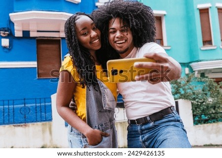 Latino friends enjoying a close-up selfie against a backdrop of urban vibrancy.