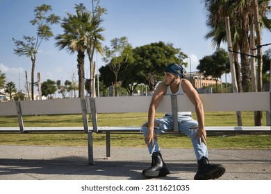 Latino and Hispanic boy, young, rebellious, with headscarf and military boots, with a lost look, sad, alone, sitting on a bench. Troubled concept, rebel, gangs, rapping, loneliness. - Shutterstock ID 2311621035