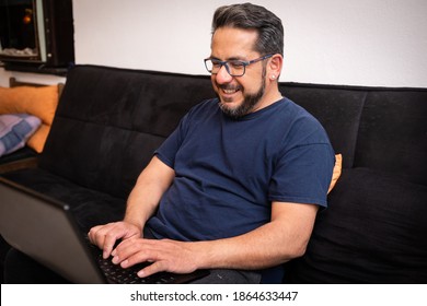 Latino Man Living With HIV Sitting On His Sofa Using A Laptop