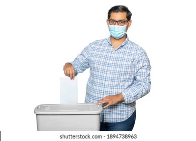 Latino  Man With Mask Voter Putting Ballot Into Voting Box. Democracy Freedom Concept Near Blue Wall Copy-Space Isolated.

