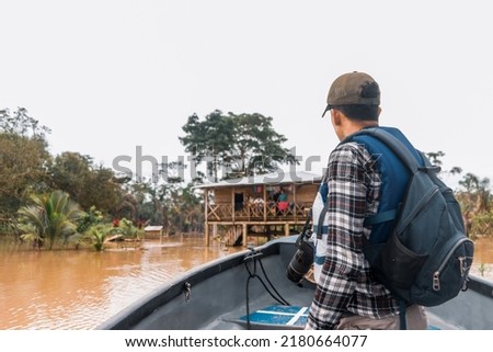 Latino man sailing a boat down a muddy river and visiting an indigenous community