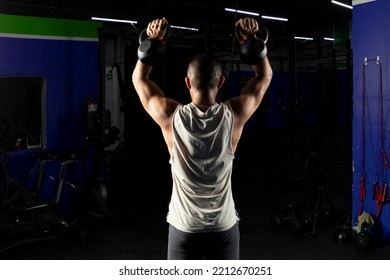 Latino Man With Sportswear, Doing Press With A Pair Of Kettlebells In A Gym